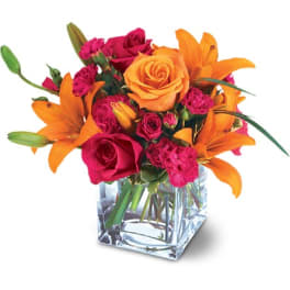 Orange lilies and pink roses in a clear square vase