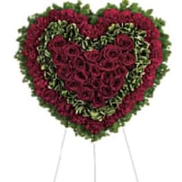 Heart-shaped floral wreath of red roses on a stand