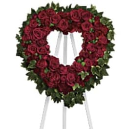 Heart-shaped wreath of red roses on a white easel