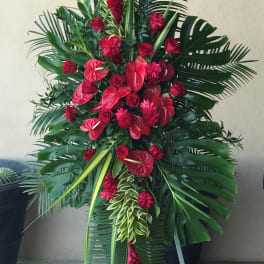 Tall red floral standing spray with tropical leaves on an easel