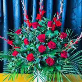 Large arrangement of red roses with tropical greenery in a white vase