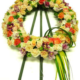 Circular floral wreath of roses and orchids on a stand