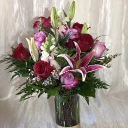 Bouquet of red and pink roses with lilies in a glass vase