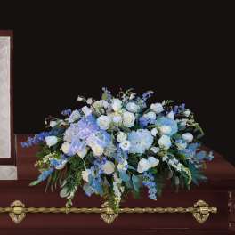 White and blue floral arrangement on a casket