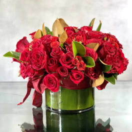 Red rose bouquet in a glass vase with burgundy ribbon