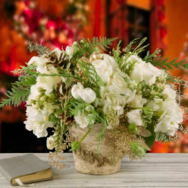 White floral arrangement in a rustic vase beside a book