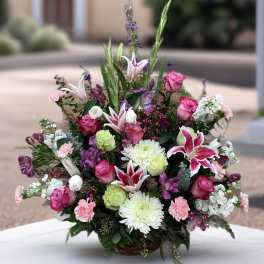 Mixed bouquet in a basket with pink roses, lilies, and white chrysanthemums