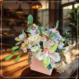 Pastel floral arrangement in a pink vase with orchids and hydrangeas