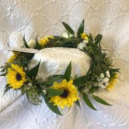 Sunflower wreath around a white cake on a textured cloth