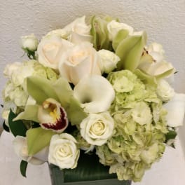 White roses, calla lilies, and hydrangeas in a square vase