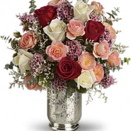 Bouquet of red, white, and peach roses in a silver vase