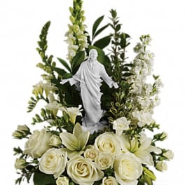 White floral arrangement with a small religious statue in the center