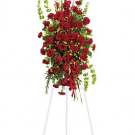 Tall standing spray of red roses and carnations on a white easel