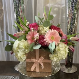 Pink and white floral arrangement in a glittery gift box with a ribbon