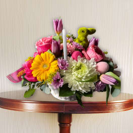 Colorful bouquet with tulips, daisies, and a green bunny figurine in a white container