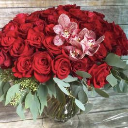 Red rose bouquet with pink orchids in a glass vase