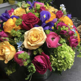 Colorful bouquet of roses, ranunculus, and irises in a vase