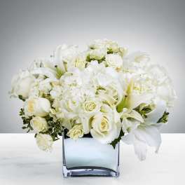 White roses and lilies arranged in a square glass vase