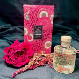 Pink rose with a patterned candle box and glass bottle