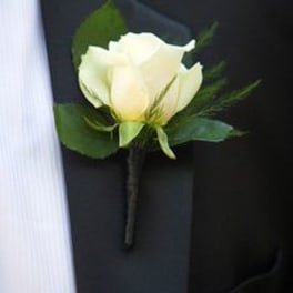 White rose boutonniere pinned to a dark suit jacket