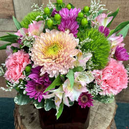 Pink and purple mixed flower arrangement in a dark vase