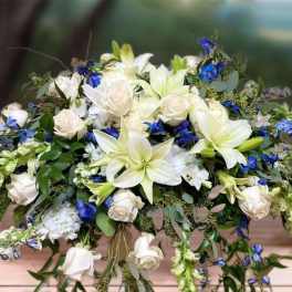 White lilies and roses with blue flowers in a low arrangement
