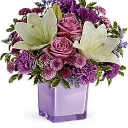 Purple and white floral arrangement in a lavender vase