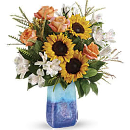 Sunflowers, peach roses, and white flowers in a blue glass vase