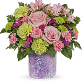 Pink roses and mixed flowers in a purple glass vase