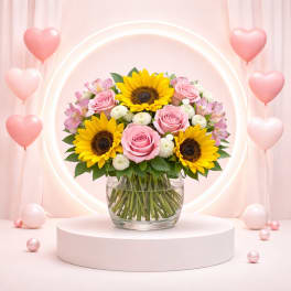 Pink roses and sunflowers in a glass vase with heart balloons