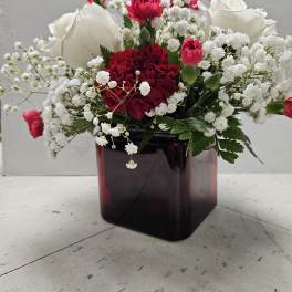 Red and white carnations with baby’s breath in a dark glass vase