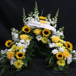 Sympathy floral spray with yellow roses, sunflowers, and white flowers
