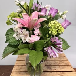 Pink lilies and purple flowers in a glass vase