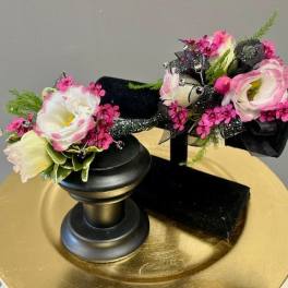 Two small floral arrangements on black stands with pink and white blooms