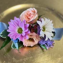 Small corsage with pink and white flowers on a blue ribbon