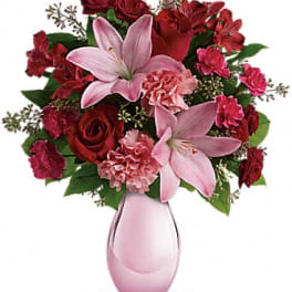 Pink lilies and red roses in a pink glass vase