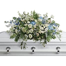 White and blue floral casket spray on a silver casket
