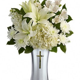 White lilies and daisies in a silver vase with a cross