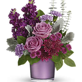 Purple and pink floral arrangement in a lavender glass vase