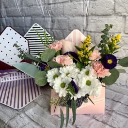 Mixed bouquet of white daisies, pink carnations, and purple flowers in a pastel gift box