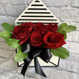 Red roses arranged in a striped gift box with a black ribbon