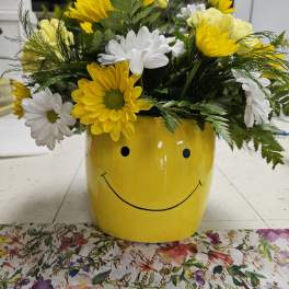 Yellow and white daisies in a smiley-face yellow pot
