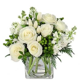 White roses and tulips arranged in a clear glass vase