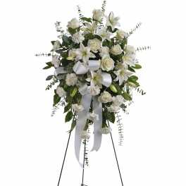 White floral standing spray on an easel with ribbon