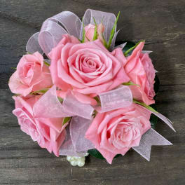 Pink rose bouquet with sheer ribbon on a dark wood surface