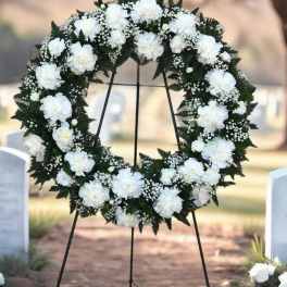 White floral wreath on a black stand at a gravesite