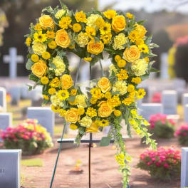 Yellow floral heart-shaped funeral wreath on a stand