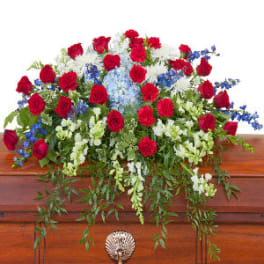 Red roses with white and blue flowers arranged on a wooden casket