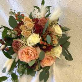 Bouquet of peach and cream roses with burgundy accents