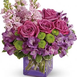 Purple and pink bouquet of roses and alstroemeria in a square vase